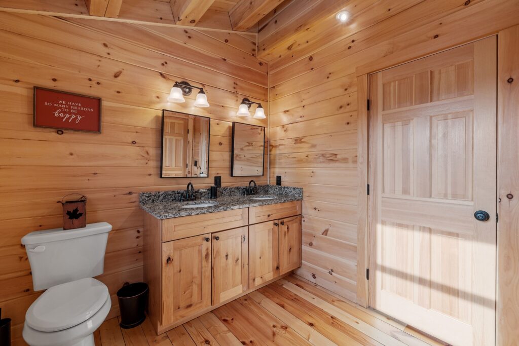 wooden bathroom with double sink and mirrors with a white toilet.