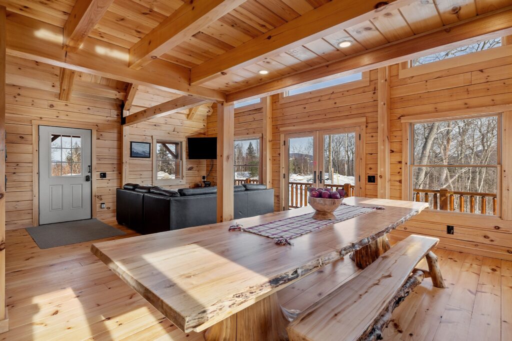 wooden interior of log cabin with a rustic dining table and living space seen in the background.